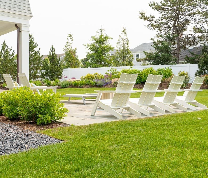 A relaxing patio with sitting area surrounded by lush grass and greenery, a property managed by CMS Landscape
