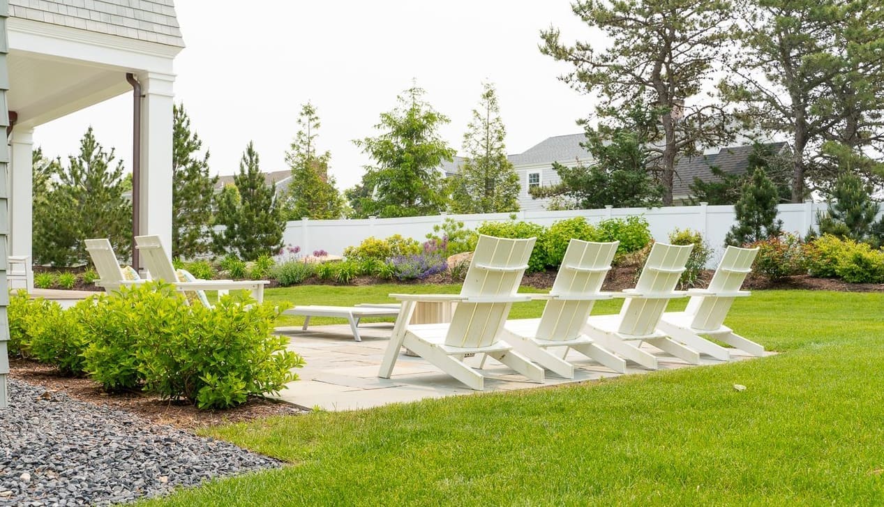 A relaxing patio with sitting area surrounded by lush grass and greenery, a property managed by CMS Landscape