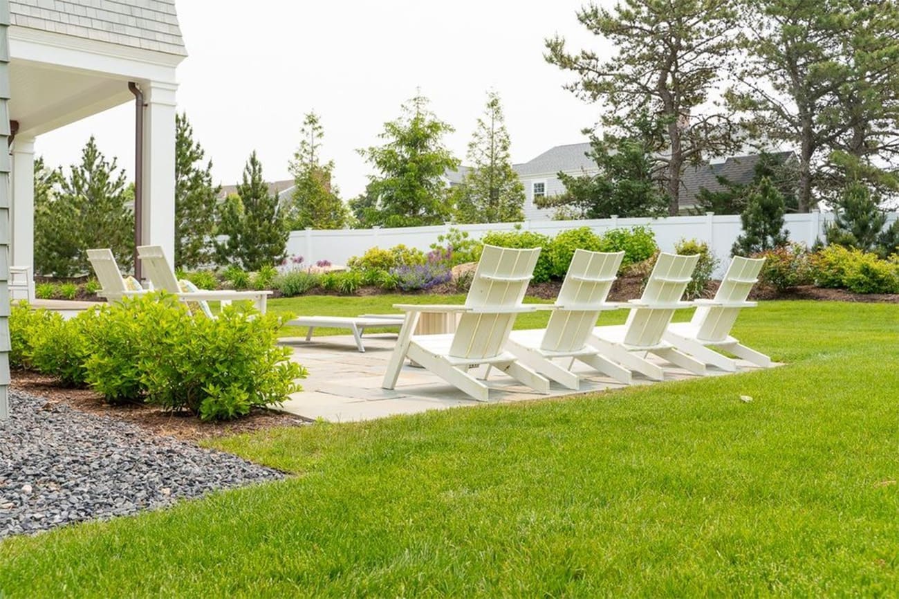 A relaxing patio with sitting area surrounded by lush grass and greenery, a property managed by CMS Landscape