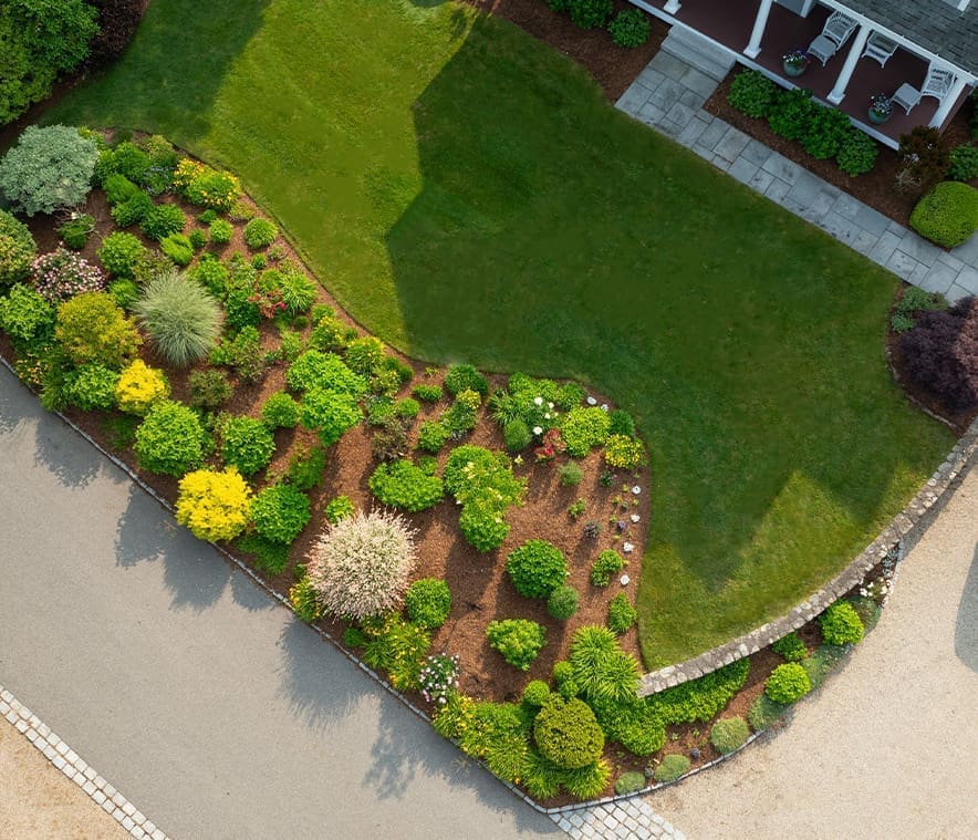 A home landscaping project managed by CMS Landscape, complete with roadside flower bed including many colorful plants and greenery.